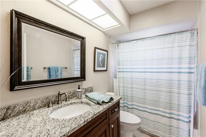 Bathroom with curtained shower, a skylight, vanity, and toilet