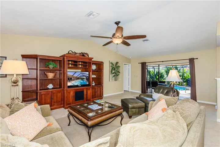 Living area featuring lofted ceiling, ceiling fan, visible vents, and baseboards