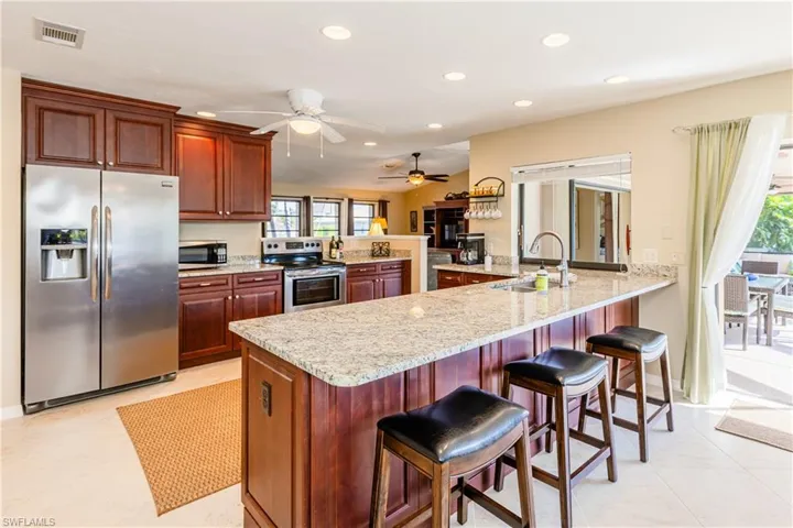 Kitchen featuring stainless steel appliances, visible vents, a sink, light stone countertops, and a peninsula