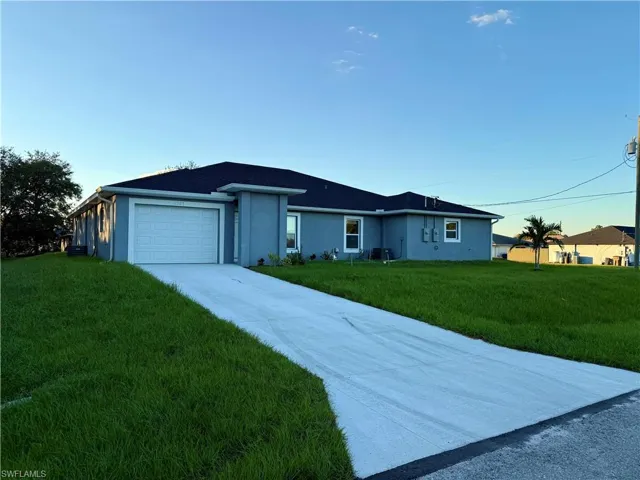 Ranch-style house featuring driveway, a front yard, stucco siding, and a garage