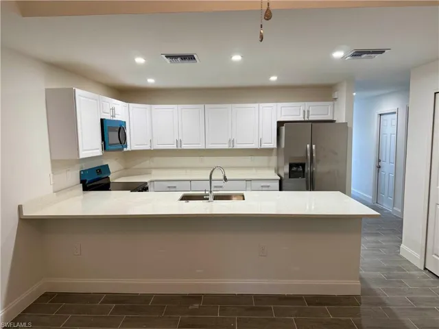 Kitchen with white cabinetry, stainless steel fridge with ice dispenser, recessed lighting, electric range, and light stone countertops