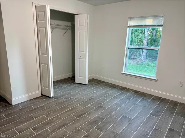 Unfurnished bedroom with a closet and wood finish floors