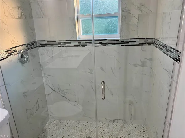 Bathroom with a marble finish shower and toilet