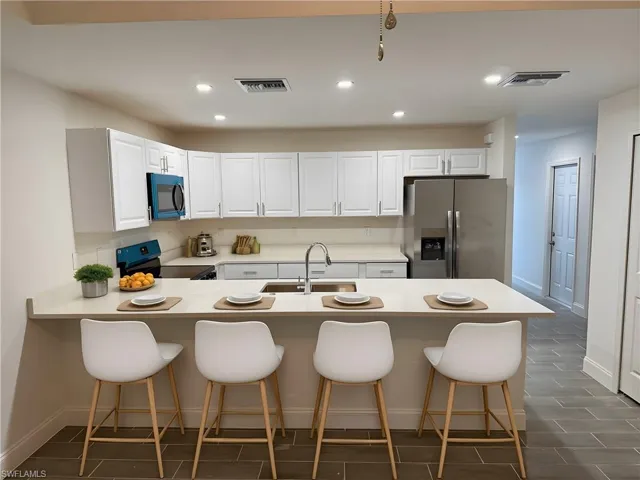Kitchen featuring a kitchen breakfast bar, stainless steel fridge with ice dispenser, recessed lighting, electric range oven, and a peninsula