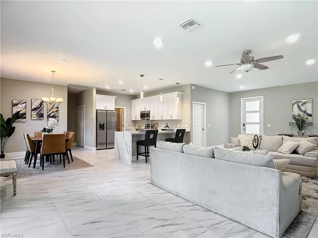 Living room featuring light tile floors and ceiling fan with notable chandelier
