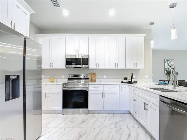 Kitchen with white cabinetry, appliances with stainless steel finishes, pendant lighting, sink, and light tile floors