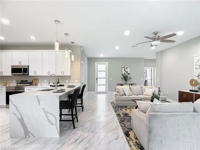 Living room featuring ceiling fan, sink, and light tile floors