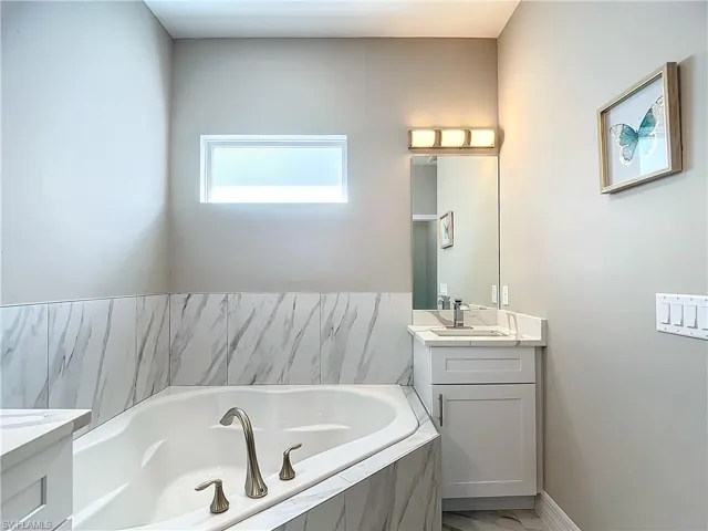 Bathroom with a relaxing tiled bath, double sink, and vanity with extensive cabinet space