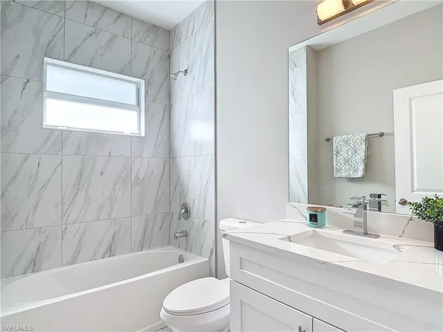 Full bathroom featuring tiled shower / bath, toilet, and large vanity