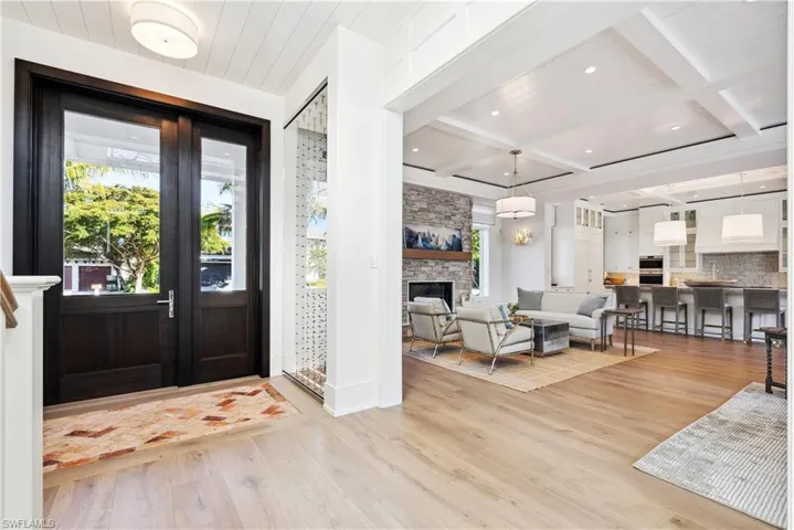 Foyer with a stone fireplace, beamed ceiling, coffered ceiling, wooden ceiling, and light wood-type flooring