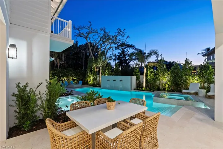 Pool at dusk featuring a patio area and an in ground hot tub