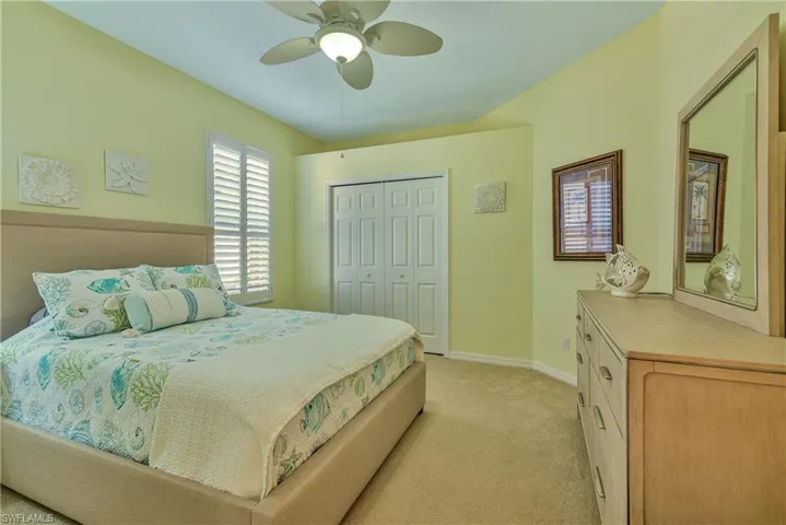 Bedroom with a ceiling fan, light colored carpet, and a closet