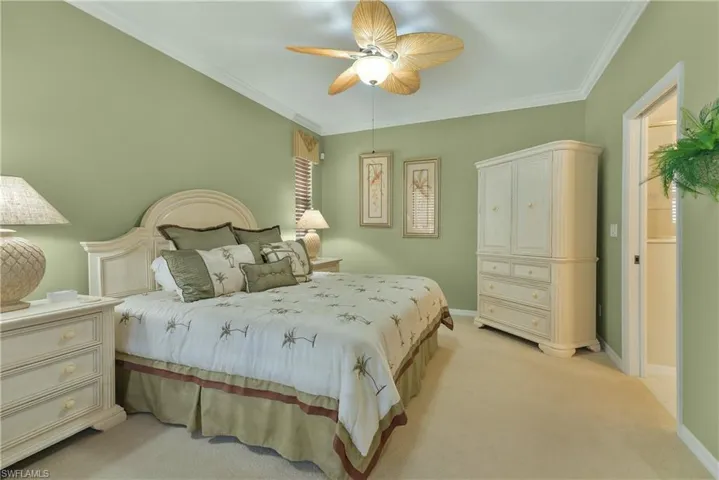 Bedroom featuring ornamental molding, light carpet, and a ceiling fan