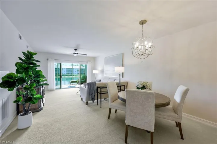 Carpeted dining area featuring ceiling fan with notable chandelier
