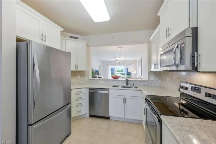 Kitchen featuring white cabinetry, appliances with stainless steel finishes, backsplash, sink, and light tile flooring