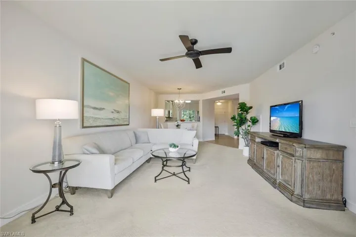 Living room featuring ceiling fan with notable chandelier