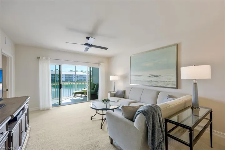 Living room with ceiling fan, a water view, and light colored carpet