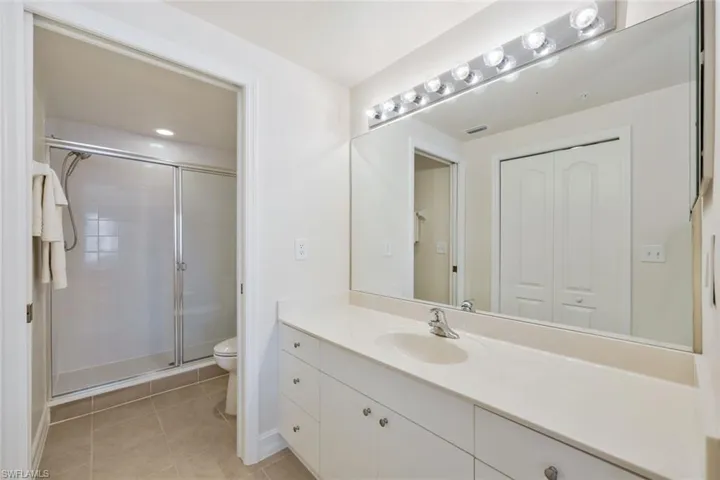 Bathroom with tile floors, an enclosed shower, large vanity, and toilet