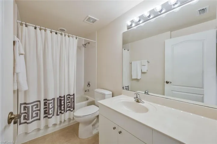 Full bathroom with tile flooring, toilet, shower / bath combo with shower curtain, and vanity