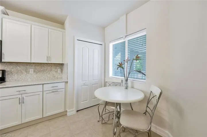 Kitchen featuring backsplash, light stone counters, white cabinetry, and light tile floors