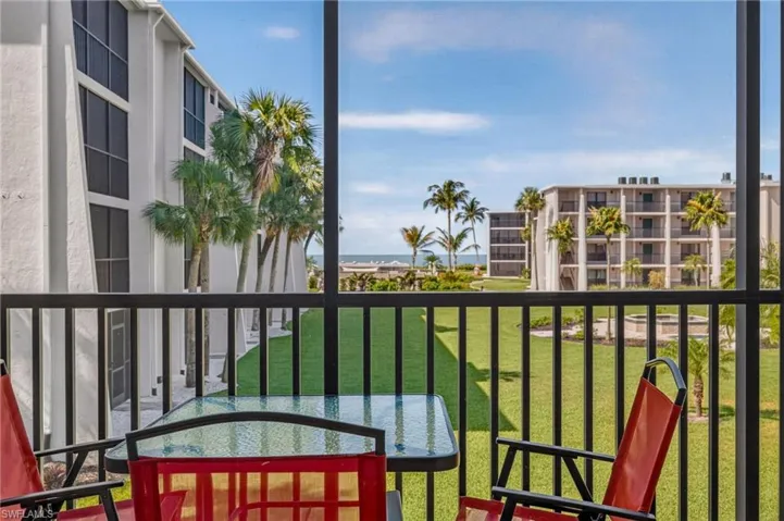 Screened outdoor living area featuring a black aluminum railing, a clear glass tabletop, and expansive green lawns