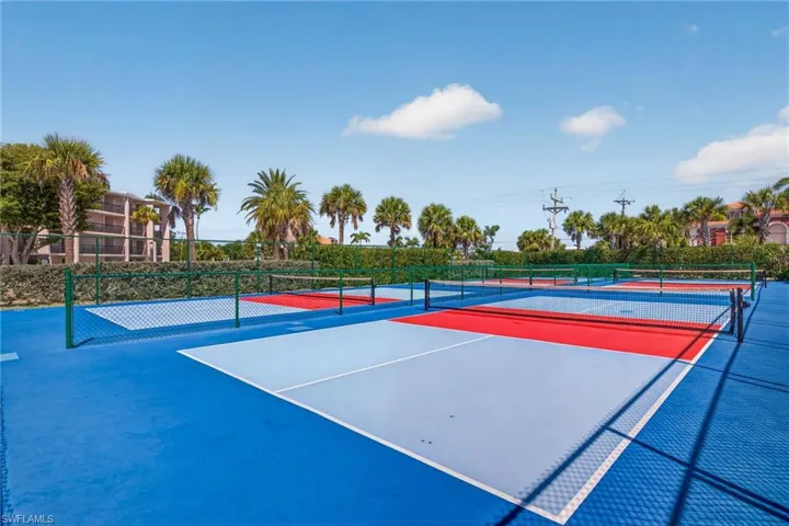 Multiple vibrant pickleball courts featuring blue, red, and light grey playing surfaces