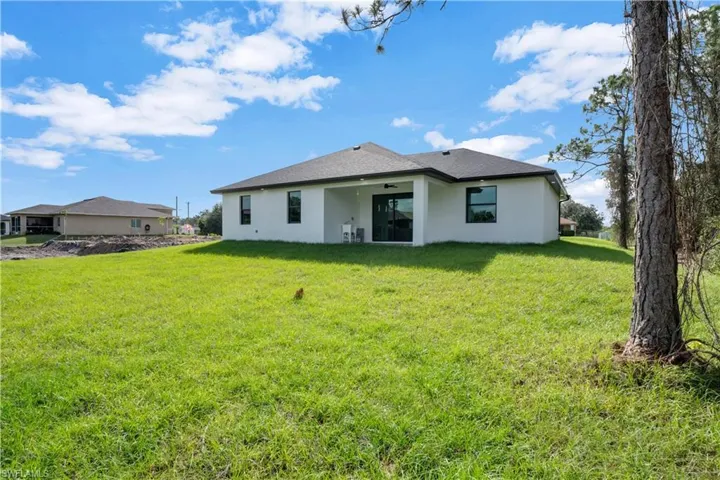 Back of property with a lawn and ceiling fan
