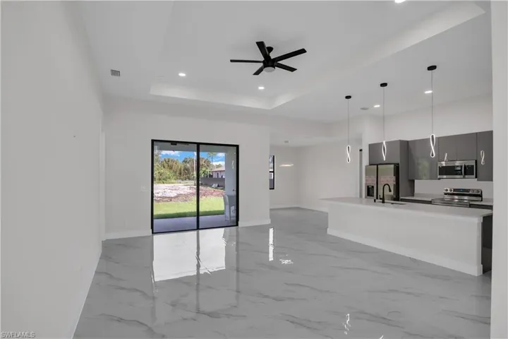 Kitchen with appliances with stainless steel finishes, a tray ceiling, ceiling fan, sink, and hanging light fixtures