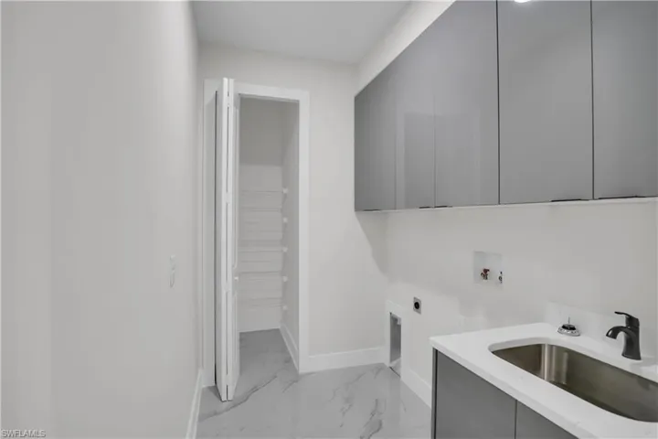 Laundry area with washer hookup, sink, cabinets, and hookup for an electric dryer