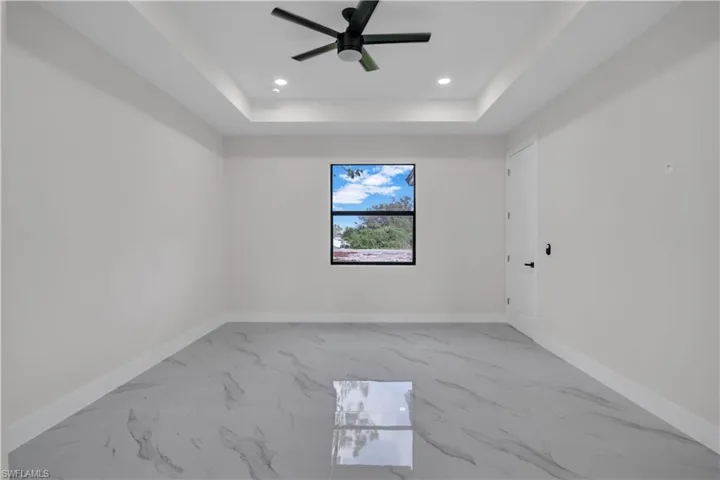 Spare room featuring a raised ceiling and ceiling fan