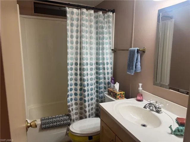 White bathtub and shower combination with a patterned curtain