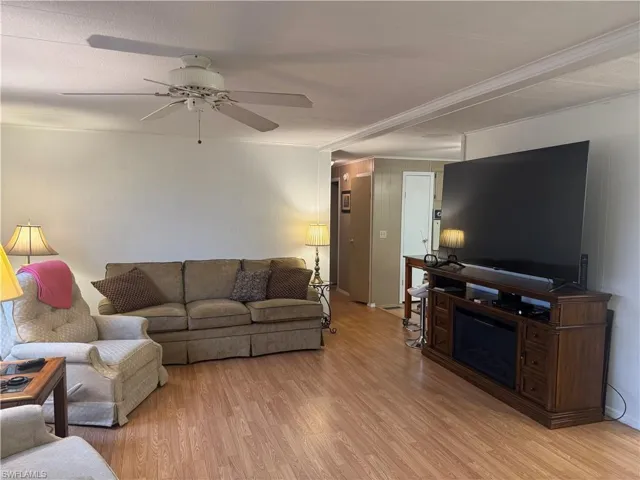Living area featuring wood-finish flooring and a white ceiling fan