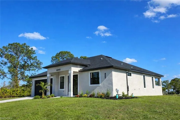 Contemporary stucco exterior with a dark shingle roof, black-framed windows, an integrated garage, and a concrete driveway