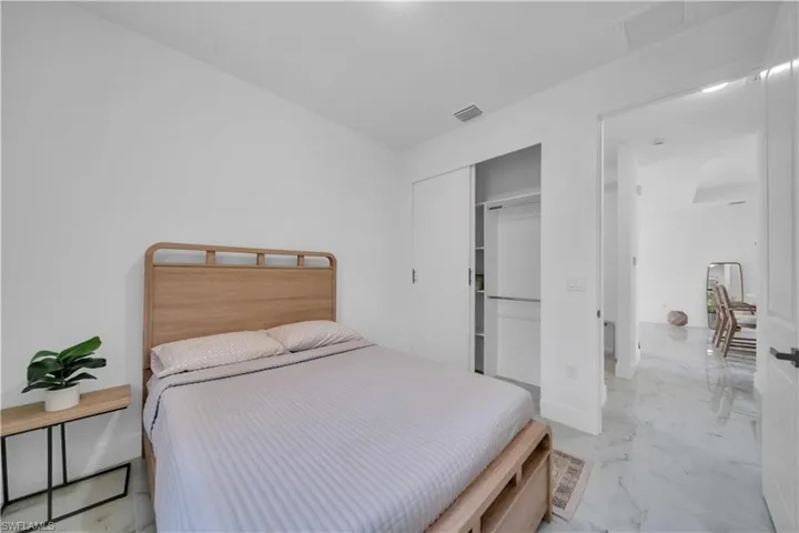 Bedroom featuring white walls, marble-finish flooring, and a sliding door closet with built-in shelving