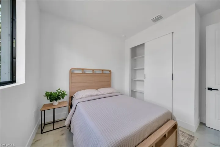 Light-filled room featuring a dark-framed window, white walls, and light-toned flooring