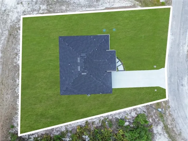 New construction home featuring a dark shingle roof, expansive green lawn, and a concrete driveway