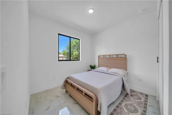 Interior space featuring a black-framed window, recessed ceiling light, white walls, white baseboards, and polished tile flooring