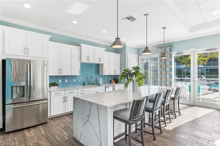Kitchen Club House featuring light stone counters, stainless steel appliances, white cabinetry, and a center island
