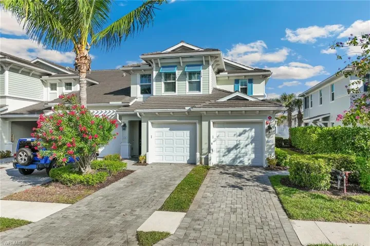 View of front of home featuring a one car garage, decorative paver driveway, and a tiled roof, with blue shutters