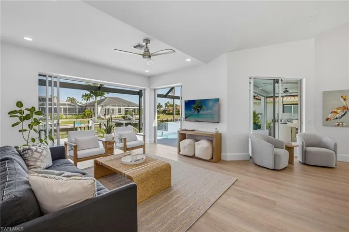 Living area with a sunroom, ceiling fan, plenty of natural light, wood finished floors, and recessed lighting