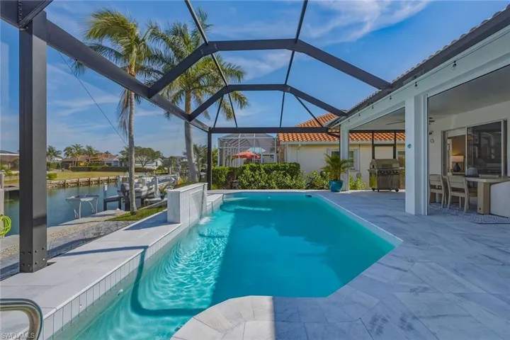 Outdoor pool featuring a sunroom, area for grilling, a patio area, glass enclosure, and a water view