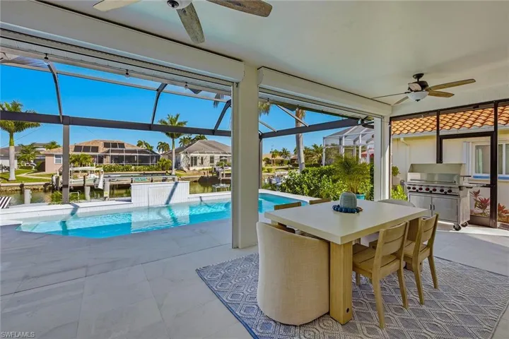 Outdoor pool featuring a lanai, a residential view, a sunroom, a patio, and an outdoor kitchen / dining area
