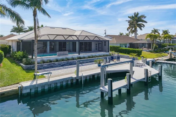 Back of property with an outdoor pool, a sunroom, glass enclosure, a patio area, and a water view