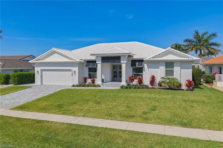 View of front of house with a garage, a tiled roof, a front yard, decorative driveway, and stucco siding