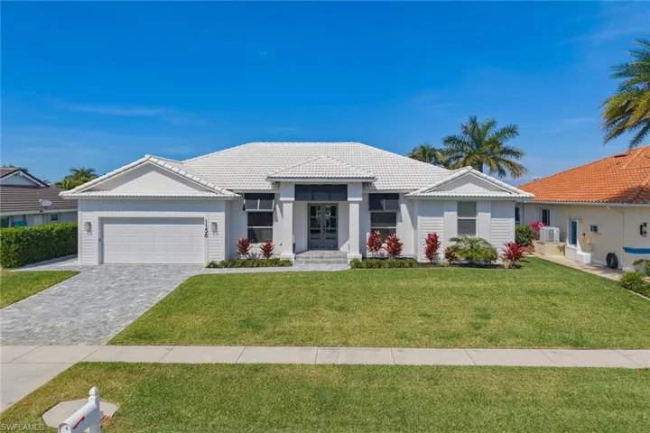 View of front of property featuring a front yard, decorative driveway, a garage, a tile roof, and stucco siding