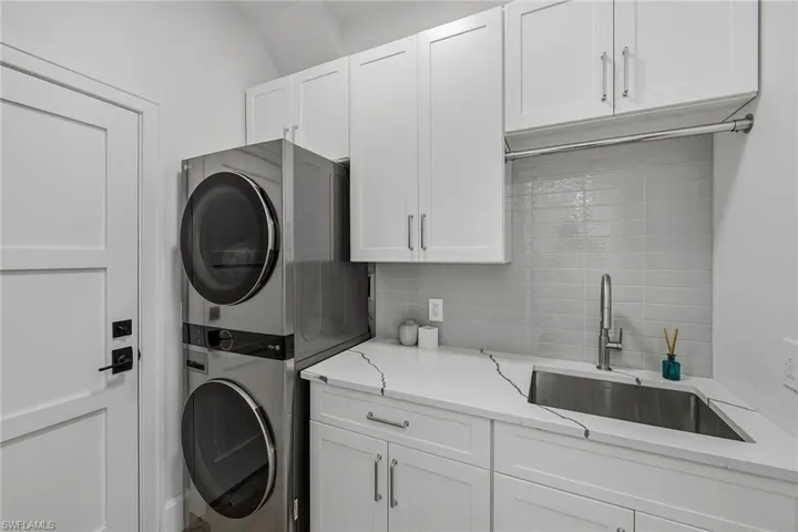 Laundry area featuring stacked washer / drying machine and cabinet space