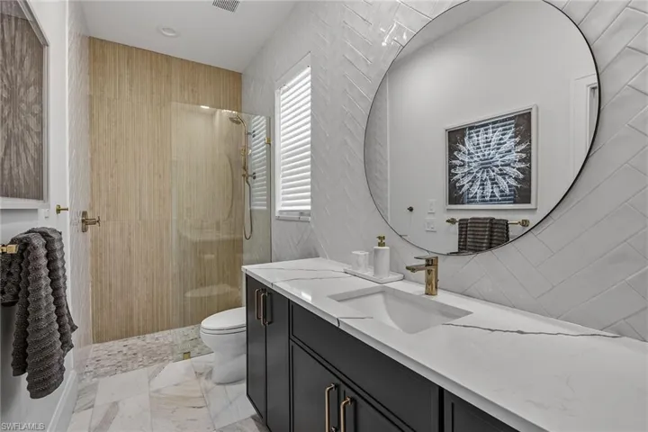 Full bath featuring walk in shower, vanity, tile walls, and light marble finish floors