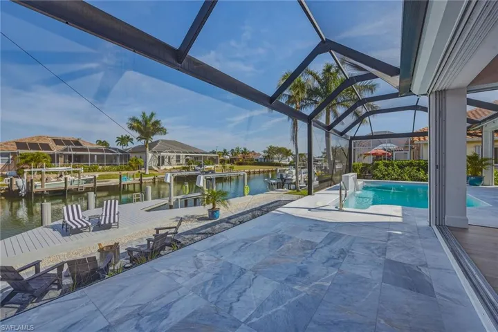 Outdoor pool with a patio, a water view, a sunroom, a dock, and glass enclosure
