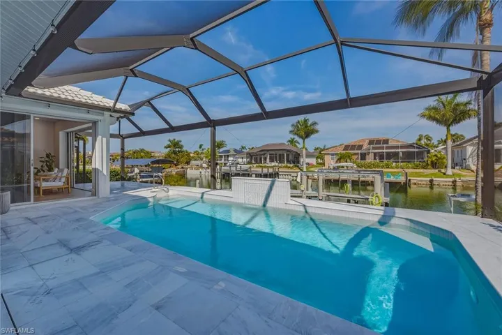 Swimming pool with a sunroom, boat lift, a patio area, and a boat dock