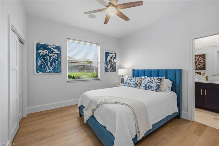 Bedroom featuring light wood-style floors, a ceiling fan, a closet, and ensuite bath